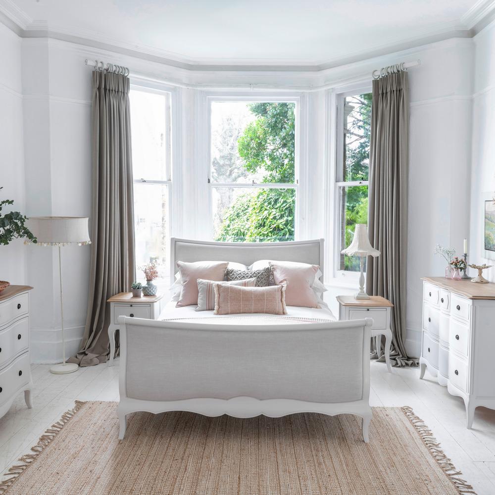 Amelie bed frame in soft dove grey with curved upholstered headboard, bow-front wooden frame, and elegant handcrafted design.