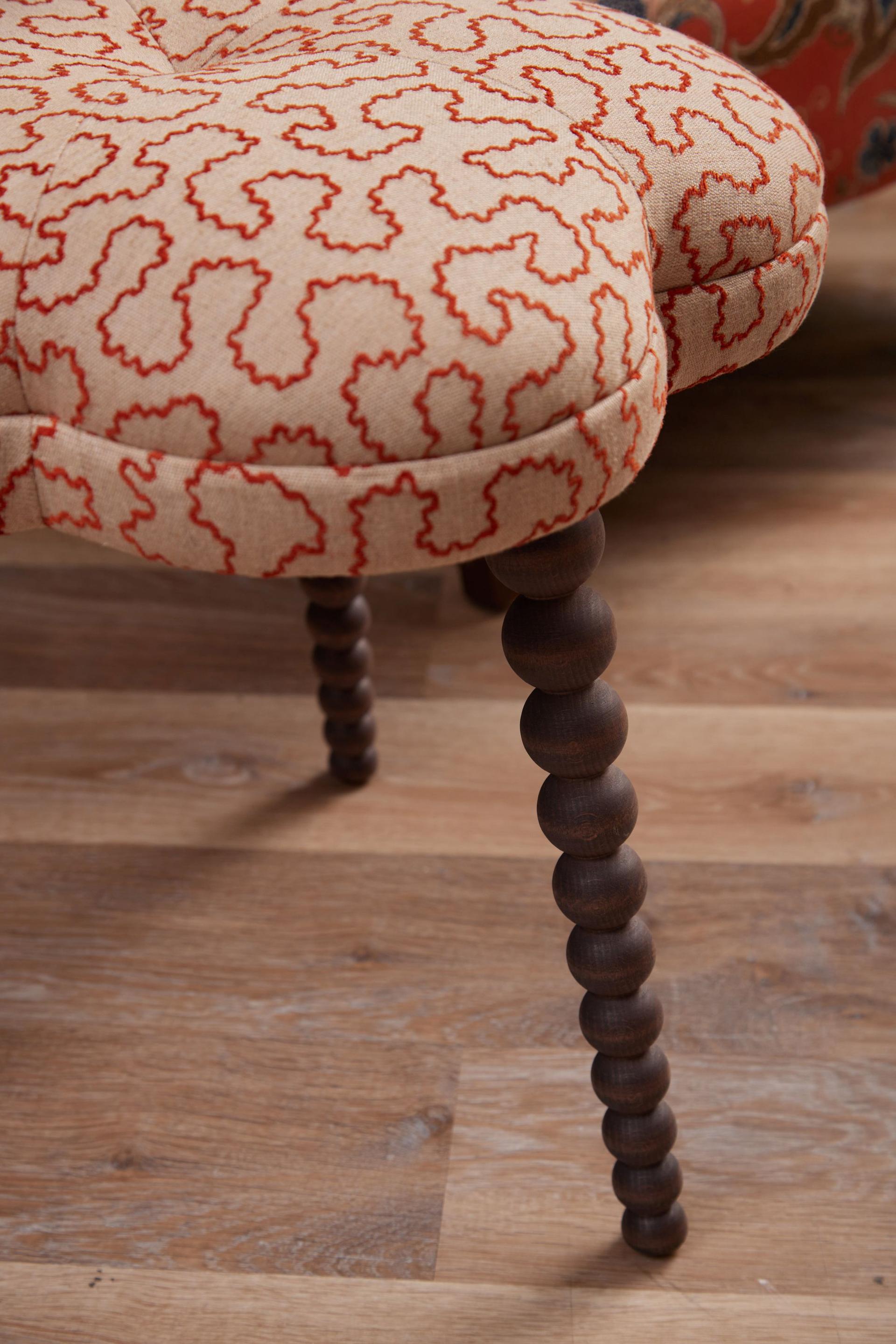 Close-up of the fully upholstered Blossom Footstool in Wiggle Ginger fabric with hand-polished solid beech legs.