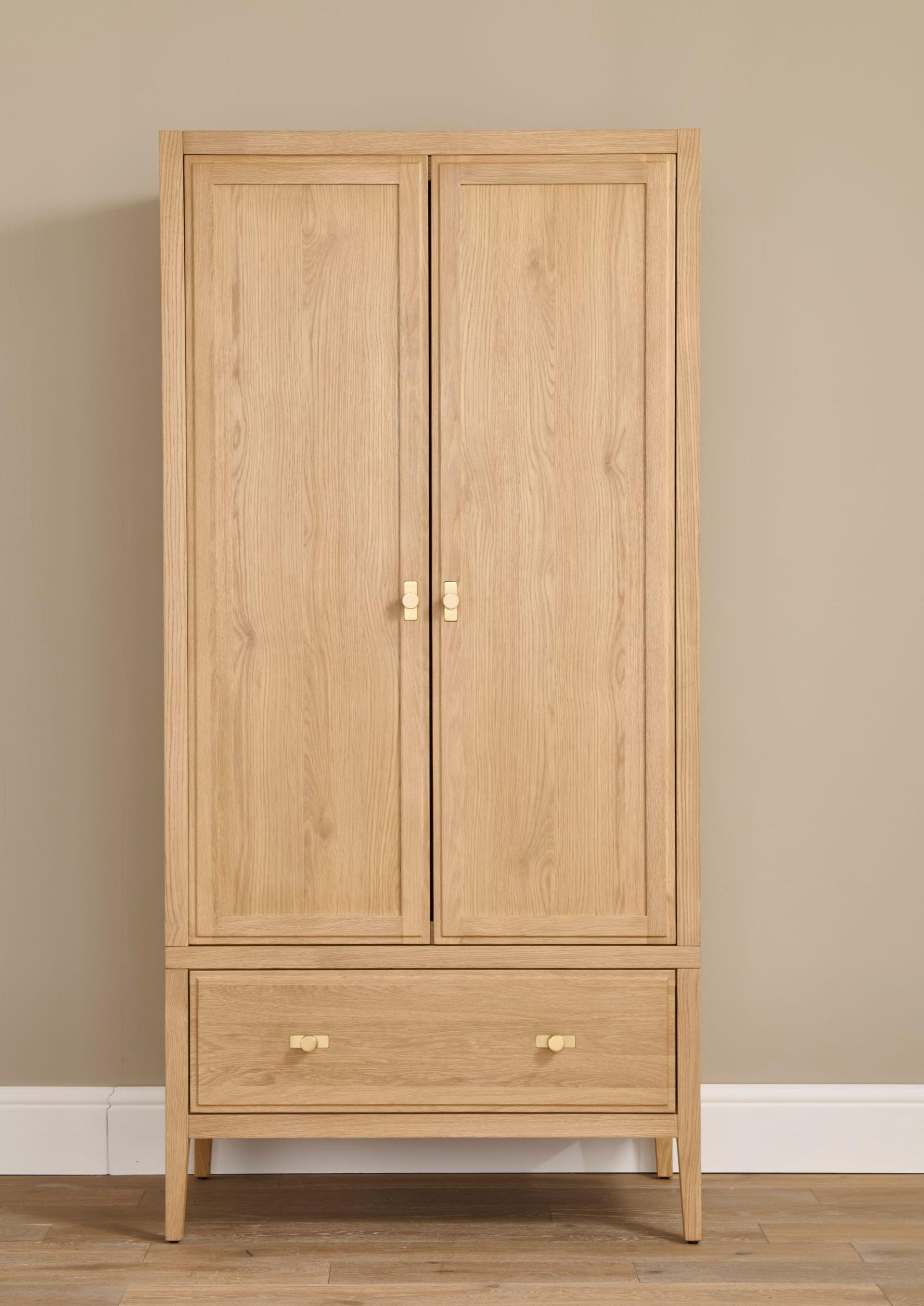 Lavinia Wardrobe in oak wood with 1 drawer and two doors against a plain wall and hardwood floor