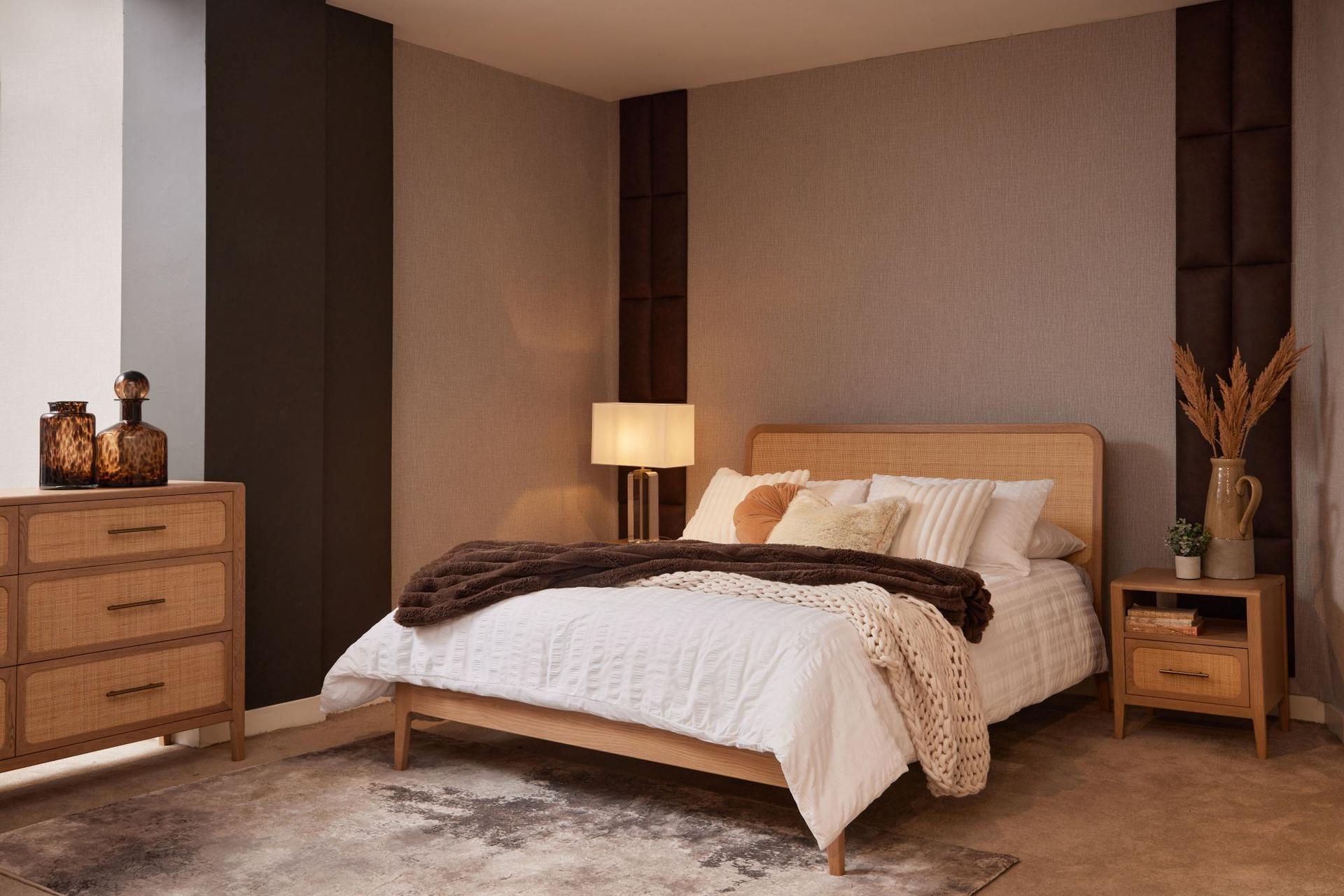 Felton oak-and-rattan bed and matching oak chest of drawers with brass handles in a bright Mediterranean bedroom.