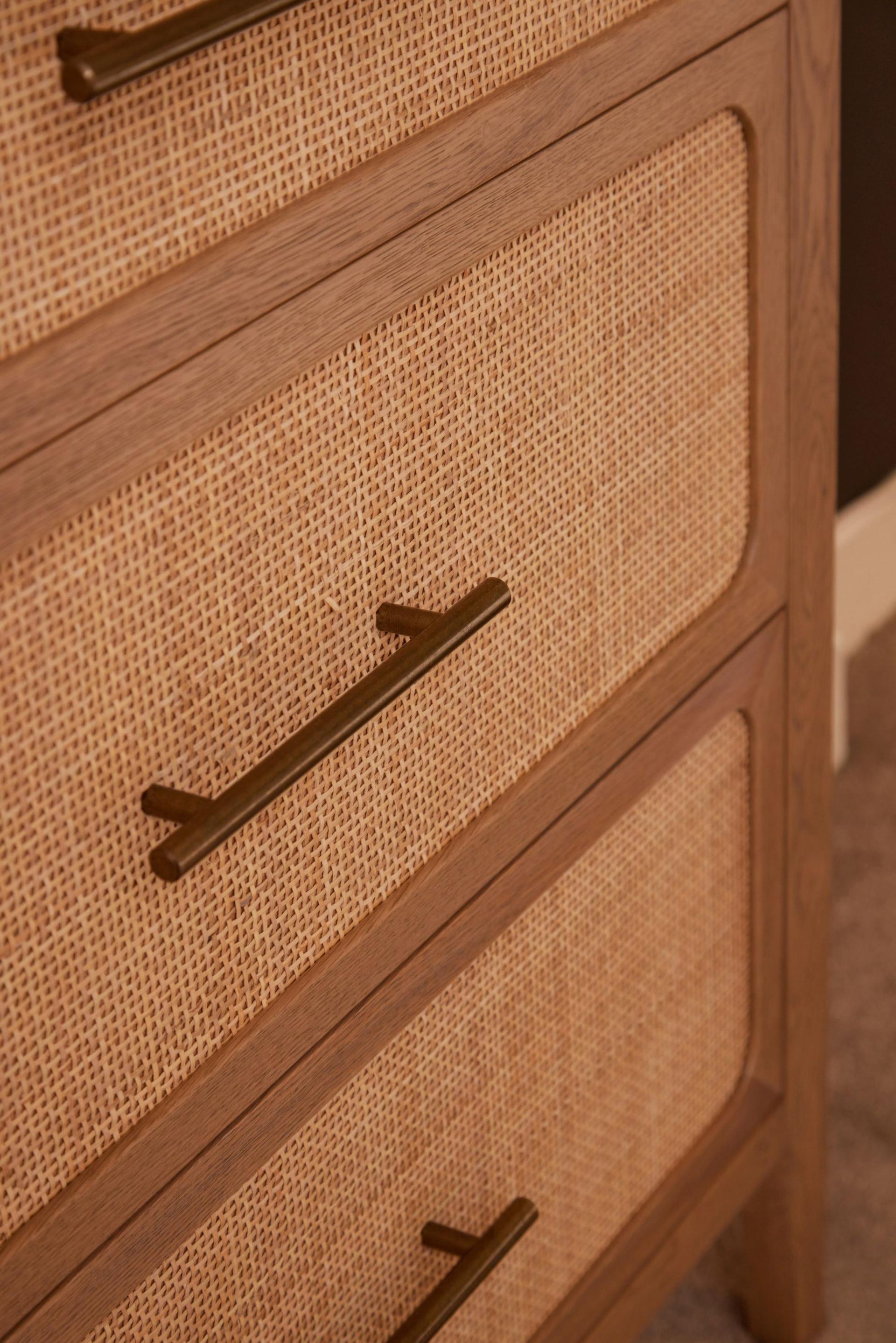 A close-up of the Felton 6-Drawer Wide Chest, showcasing its natural rattan-paneled drawers, American oak frame, and burnished brass handles.