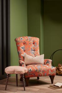 Hawthorne Armchair upholstered in vibrant Uhura Tomato floral fabric, featuring a hand-buttoned high back and a matching footstool.