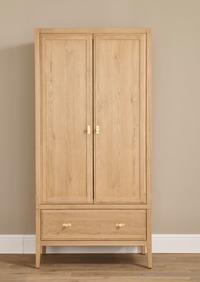 Lavinia Wardrobe in oak wood with 1 drawer and two doors against a plain wall and hardwood floor
