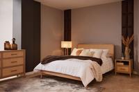 Felton oak-and-rattan bed and matching oak chest of drawers with brass handles in a bright Mediterranean bedroom.