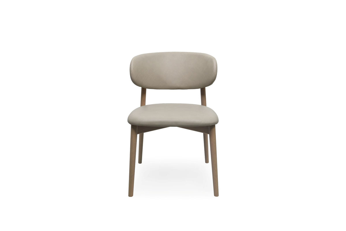 A modern upholstered dining chair with a curved backrest, upholstered in a light stone fabric, supported by a light oak wood frame, shown from the front on a white background.