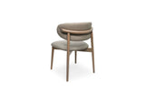 A modern upholstered dining chair with a curved backrest, upholstered in a light stone fabric, supported by a light oak wood frame, shown from the front on a white background.