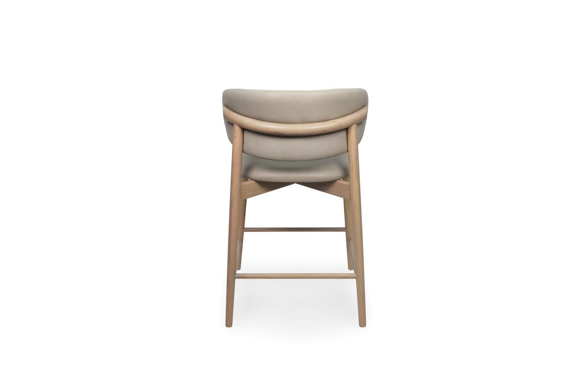 A modern high-back bar stool with a curved upholstered backrest and seat in a light taupe fabric, supported by a light natural wood frame, shown from the front on a white background.
