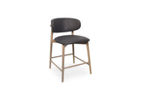 A modern bar stool with a dark chocolate upholstered seat and curved backrest, supported by a light natural wood frame with crossbars, shown on a plain white background.